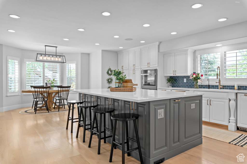 Kitchen featuring a kitchen island, pendant lighting, light hardwood / wood-style flooring, and white cabinets