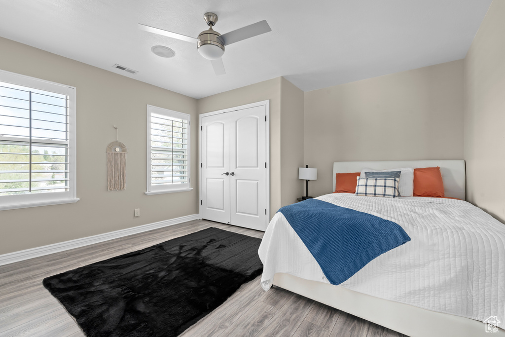 Bedroom with a closet, light hardwood / wood-style floors, and ceiling fan