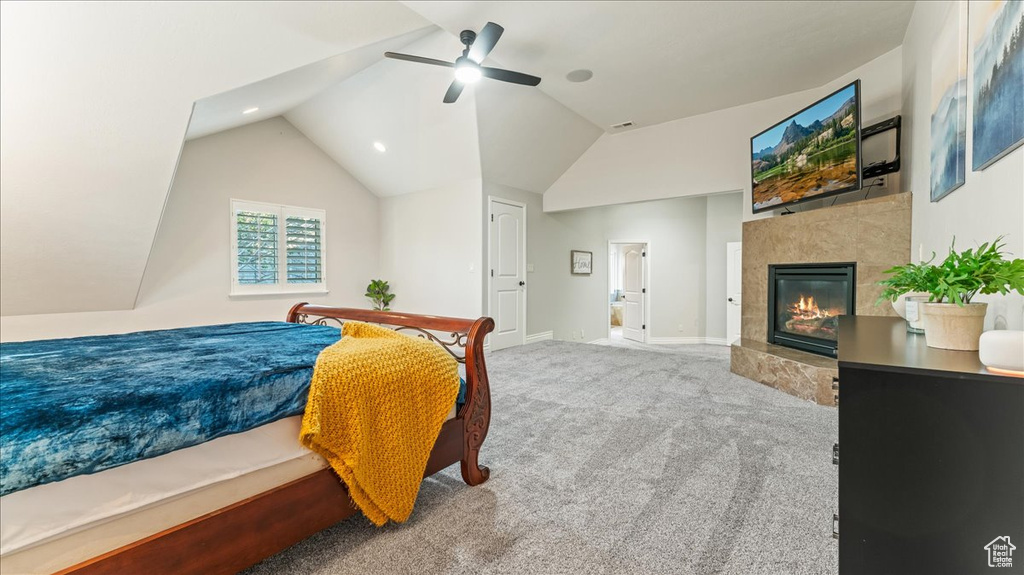 Bedroom featuring light carpet, a fireplace, ceiling fan, and lofted ceiling
