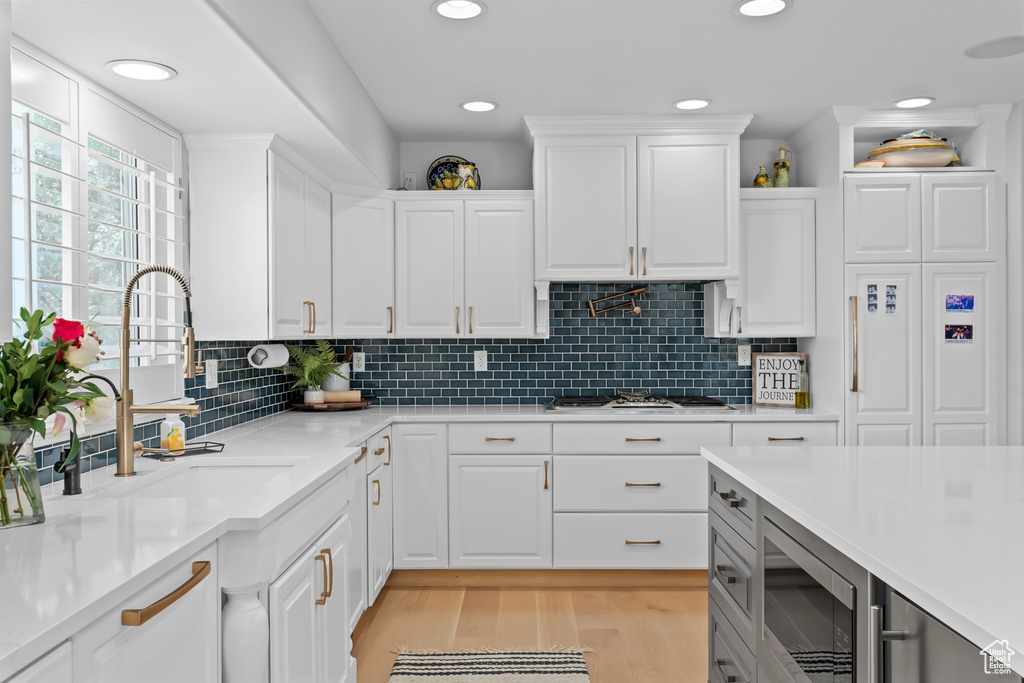 Kitchen featuring white cabinets, tasteful backsplash, and light wood-type flooring