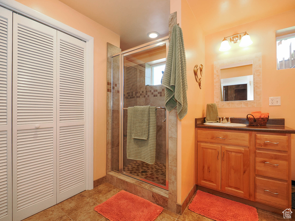 Bathroom featuring a wealth of natural light, a shower with door, tile flooring, and vanity