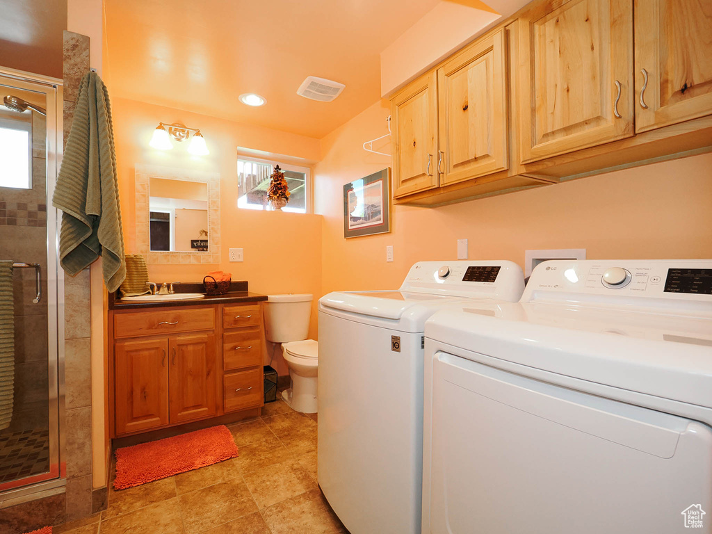 Laundry area featuring sink, a healthy amount of sunlight, washing machine and dryer, and light tile floors