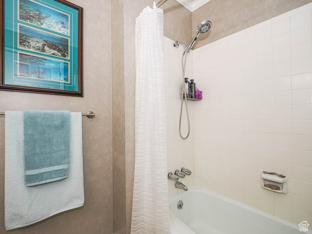 Bathroom featuring shower / tub combo and ornamental molding