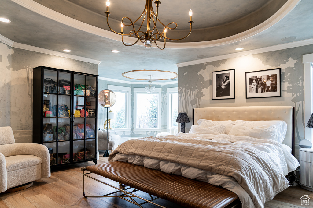 Bedroom featuring ornamental molding, light hardwood / wood-style floors, a chandelier, and a tray ceiling