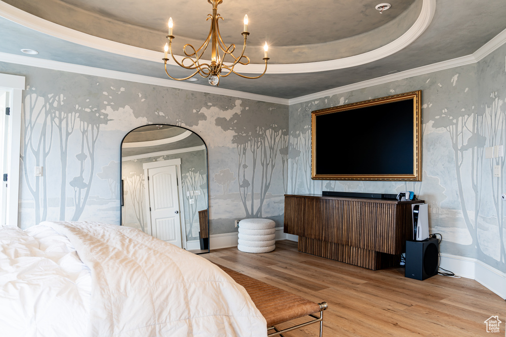 Bedroom featuring light hardwood / wood-style floors, a chandelier, crown molding, and a tray ceiling
