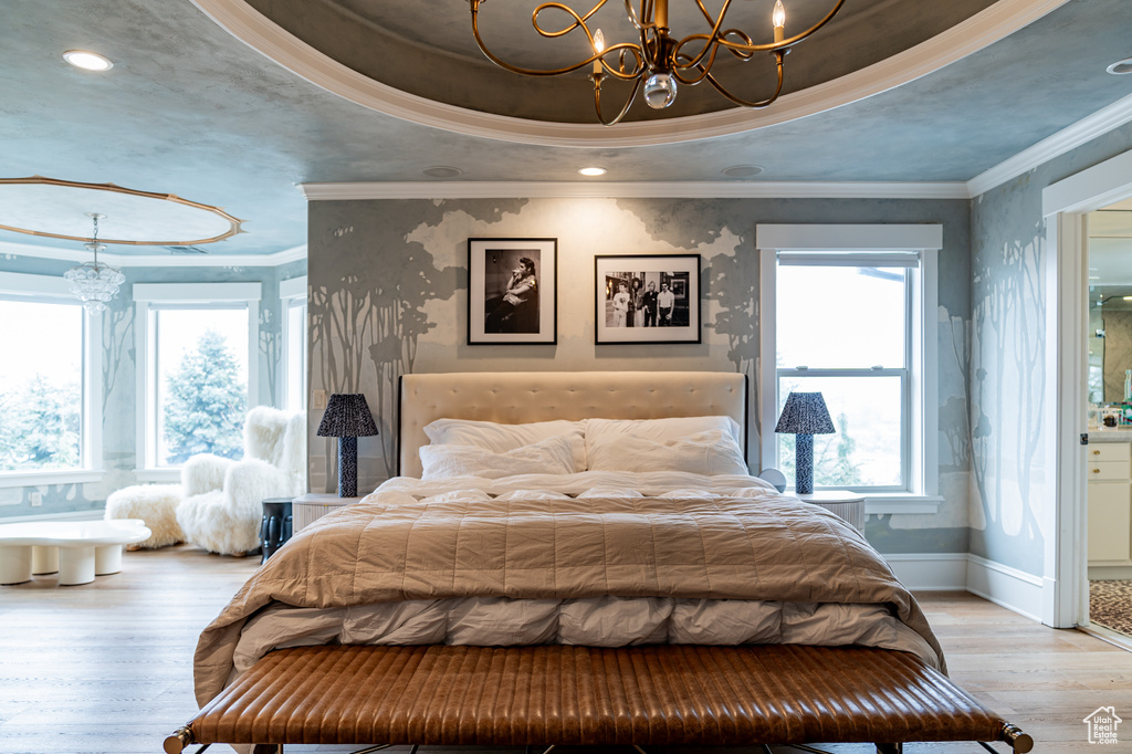 Bedroom with light hardwood / wood-style flooring, a raised ceiling, a notable chandelier, and ornamental molding