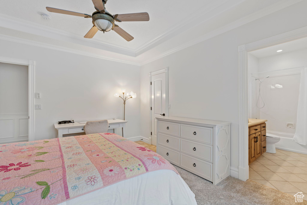 Tiled bedroom featuring ornamental molding, connected bathroom, ceiling fan, and a tray ceiling