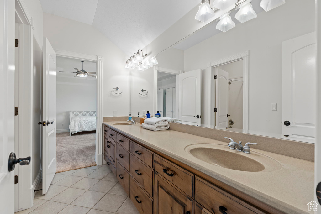 Bathroom with ceiling fan, vaulted ceiling, dual vanity, and tile flooring