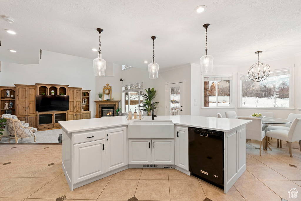 Kitchen featuring light tile floors, sink, white cabinetry, hanging light fixtures, and black dishwasher