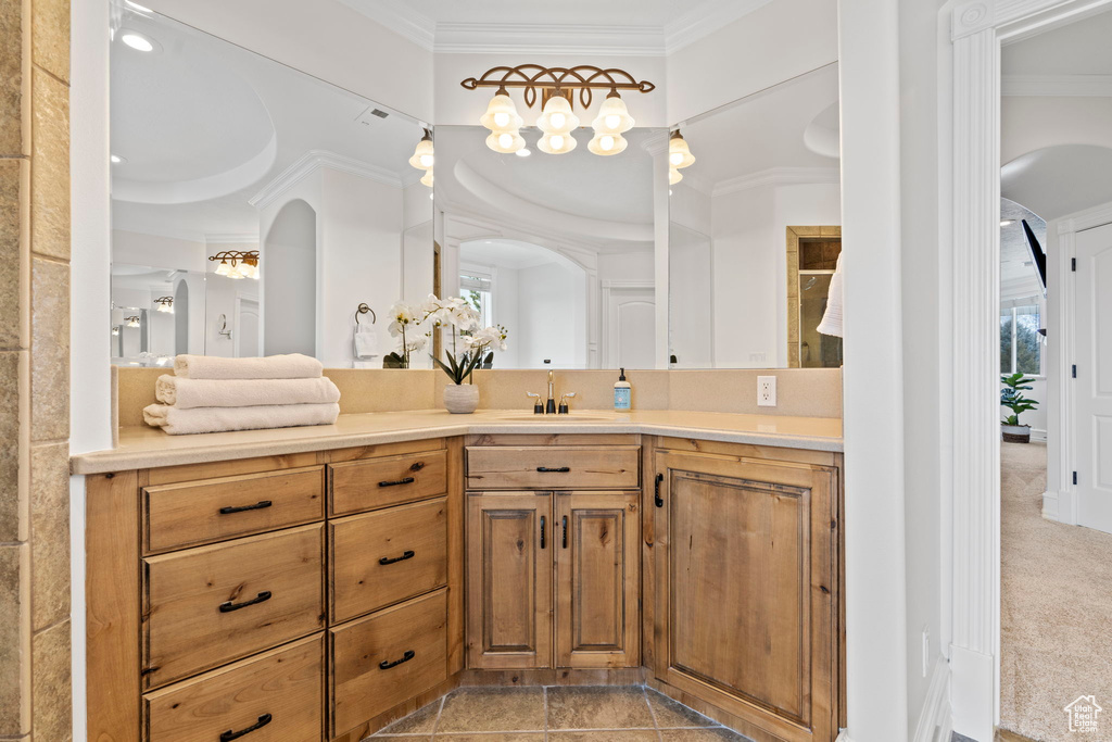 Bathroom with ornamental molding, tile floors, vanity, and a raised ceiling