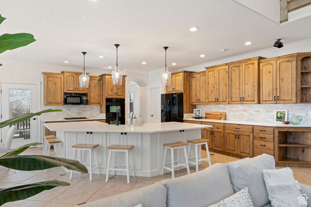 Kitchen featuring a center island with sink, a breakfast bar, and black appliances