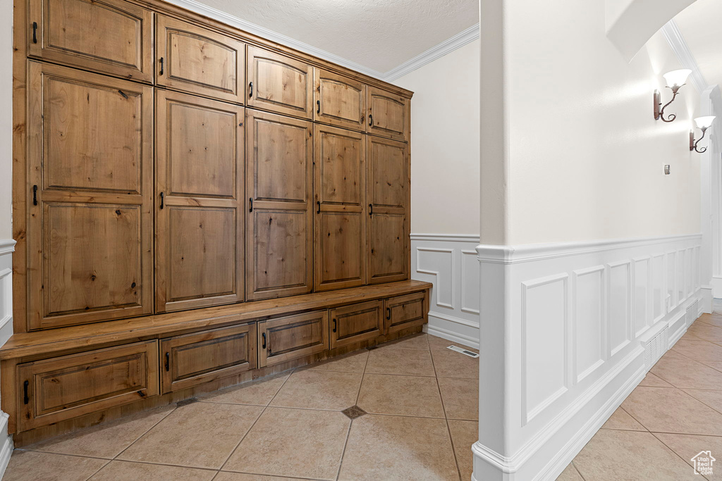 Mudroom featuring ornamental molding, a textured ceiling, and light tile floors