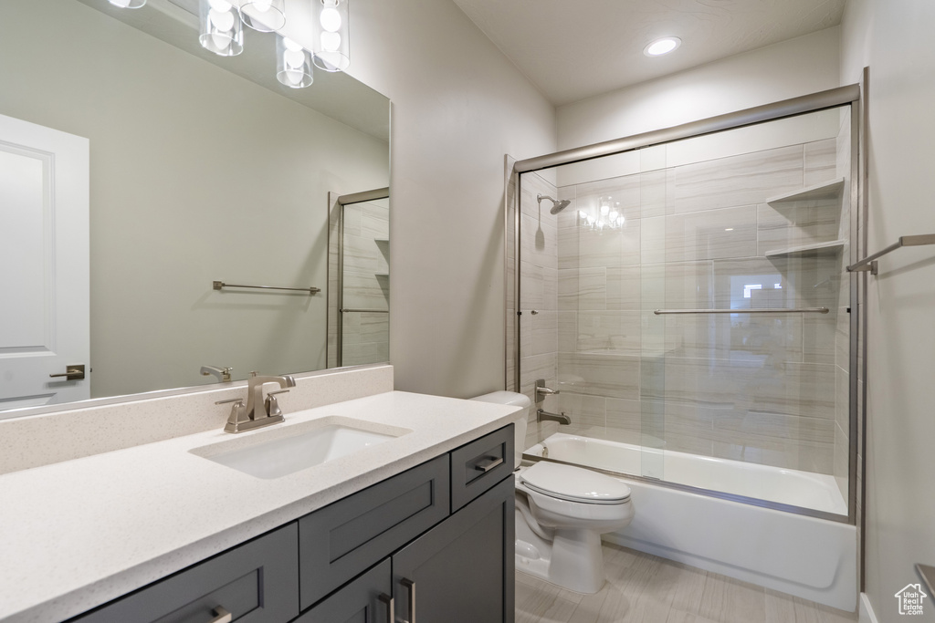 Full bathroom featuring tile flooring, toilet, shower / bath combination with glass door, and large vanity
