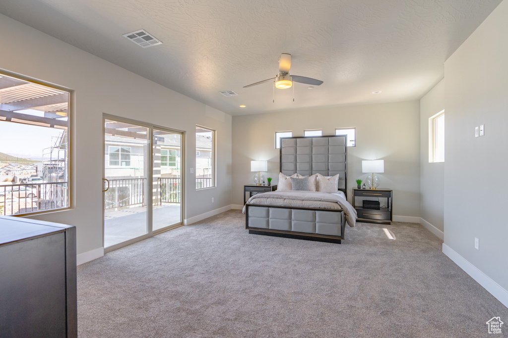 Bedroom with ceiling fan, light carpet, and access to outside