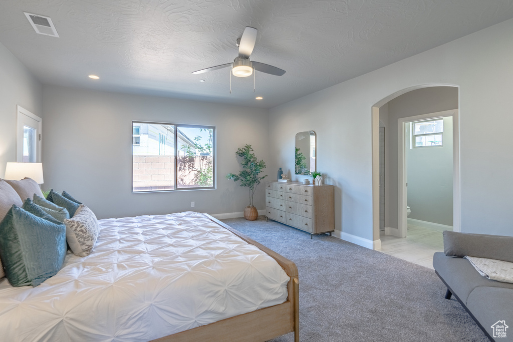 Bedroom with light colored carpet, ceiling fan, and multiple windows