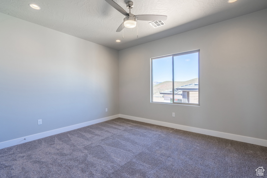 Unfurnished room featuring ceiling fan and dark carpet