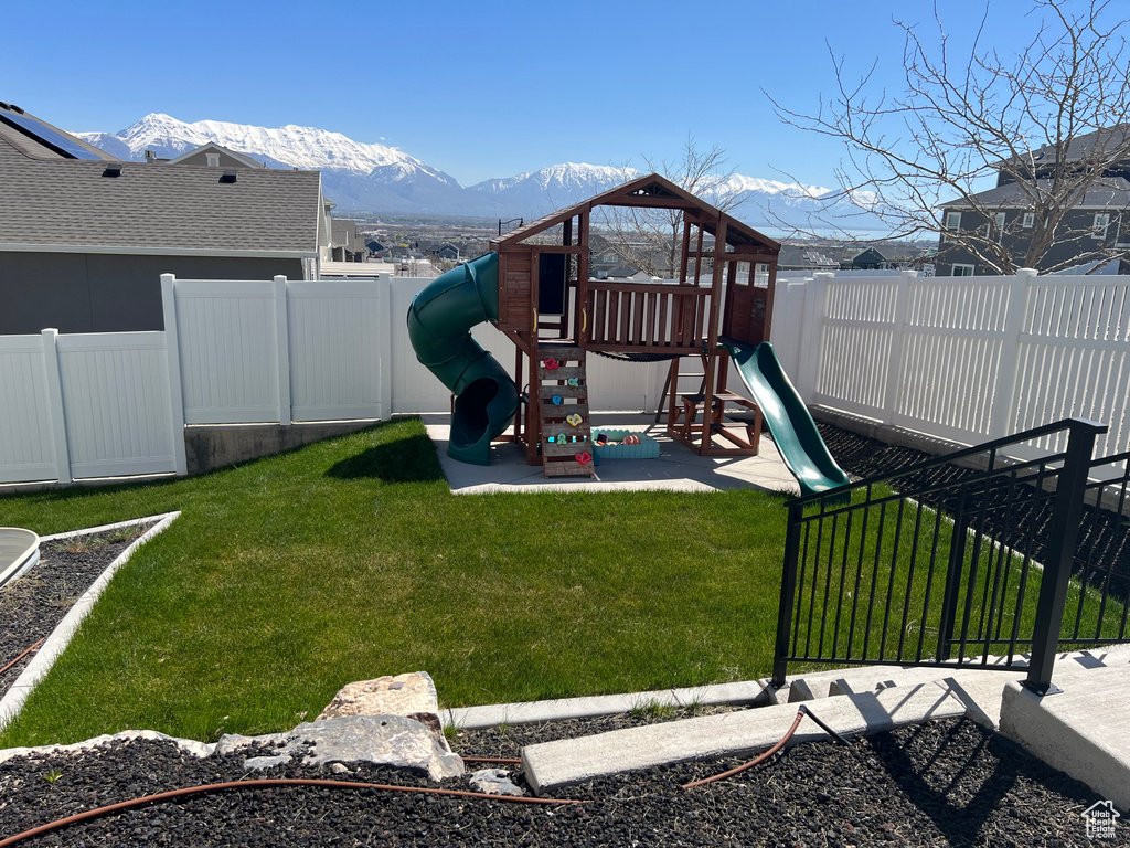 View of jungle gym with a mountain view and a yard