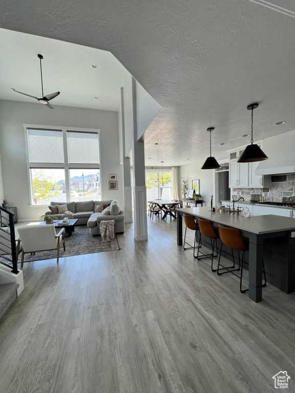 Interior space with backsplash, pendant lighting, light hardwood / wood-style flooring, and white cabinetry