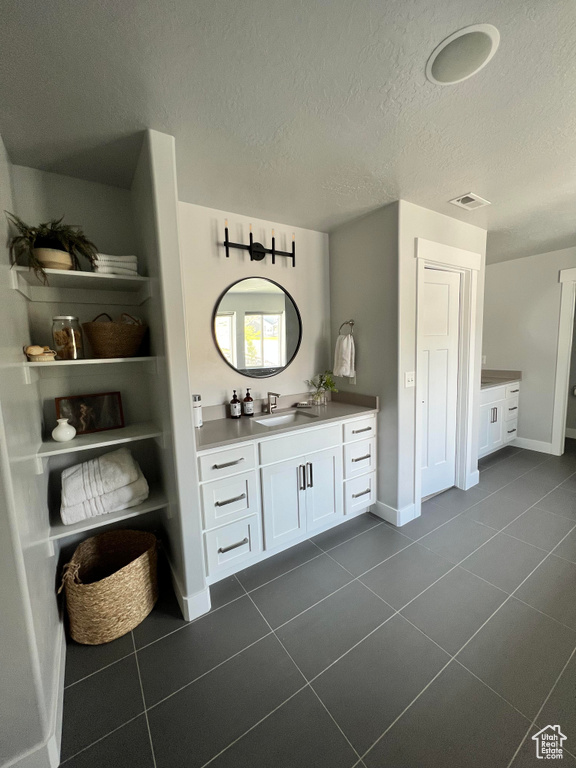 Bathroom featuring tile flooring, vanity, and a textured ceiling