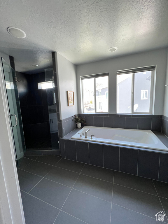 Bathroom featuring tile floors, separate shower and tub, and a textured ceiling