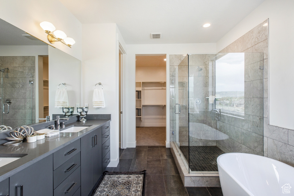 Bathroom featuring tile walls, double vanity, tile flooring, and separate shower and tub