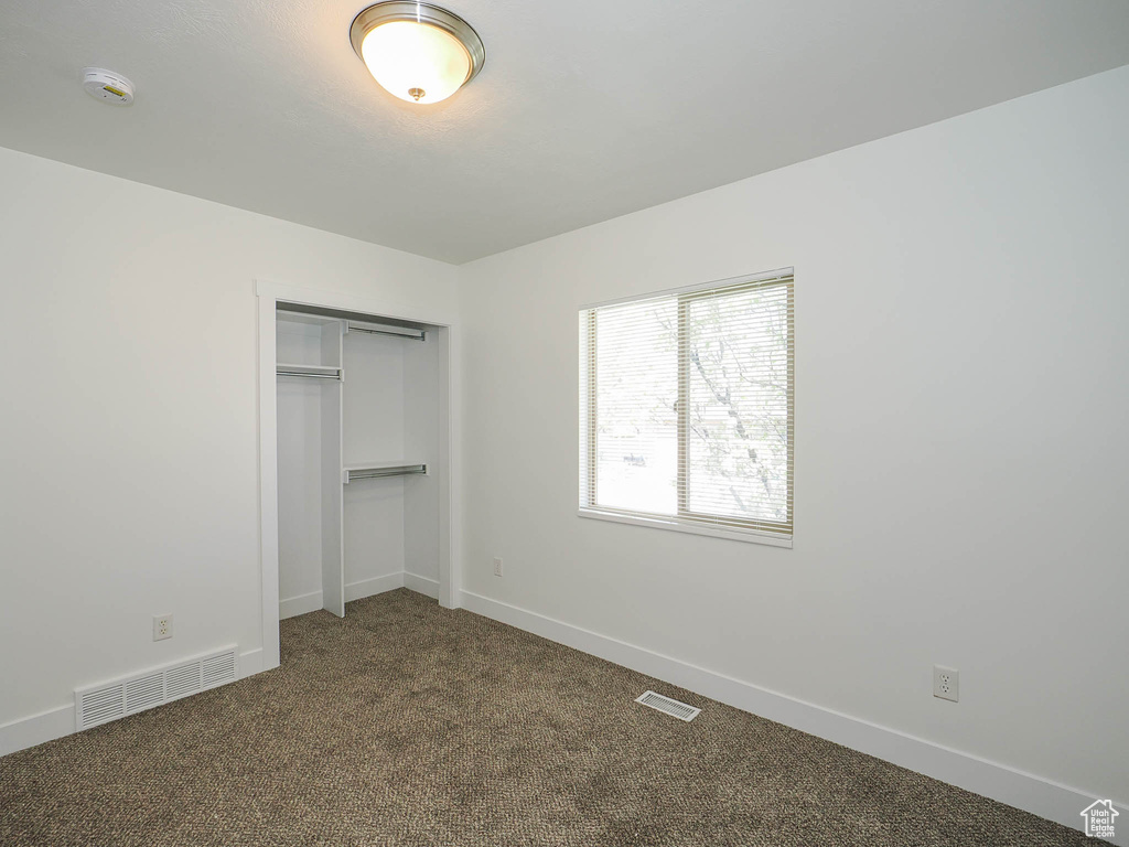 Unfurnished bedroom with a closet and dark carpet