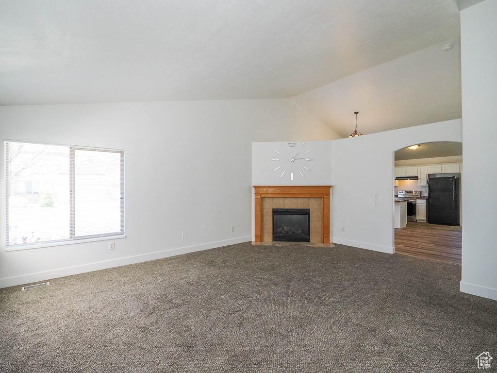 Unfurnished living room featuring lofted ceiling, a fireplace, and carpet floors