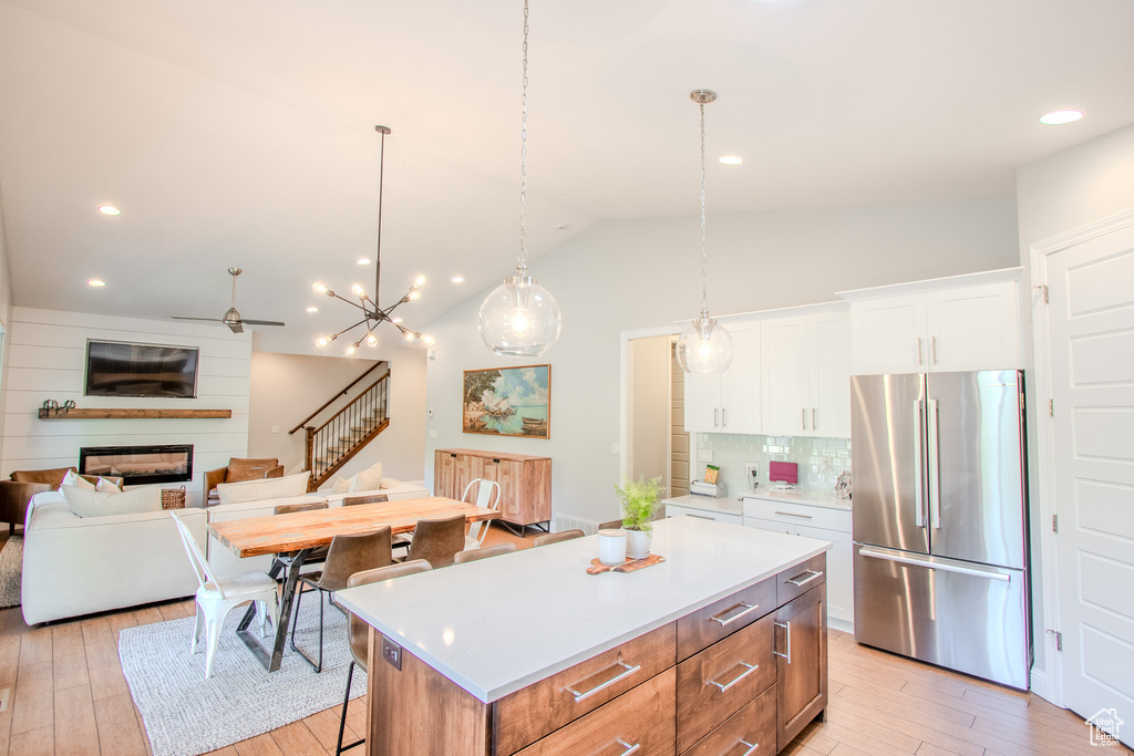 Kitchen featuring a center island, white cabinets, light hardwood / wood-style floors, stainless steel refrigerator, and backsplash