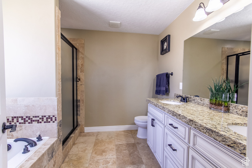 Full bathroom with tile flooring, large vanity, a textured ceiling, double sink, and toilet
