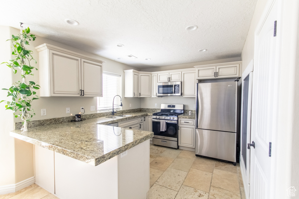 Kitchen featuring sink, appliances with stainless steel finishes, kitchen peninsula, and light tile floors
