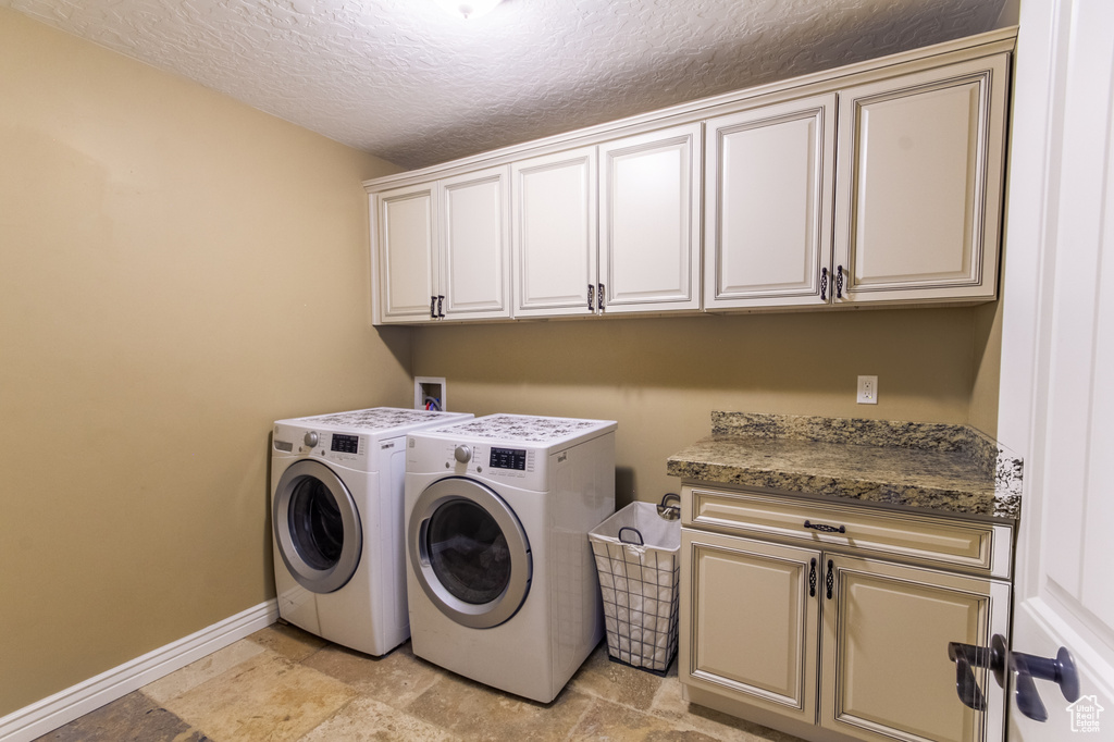 Washroom with cabinets, light tile floors, a textured ceiling, hookup for a washing machine, and independent washer and dryer