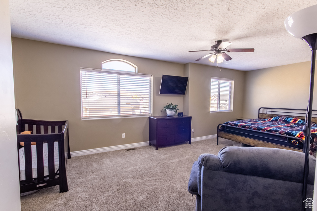Bedroom featuring light colored carpet, a textured ceiling, and ceiling fan