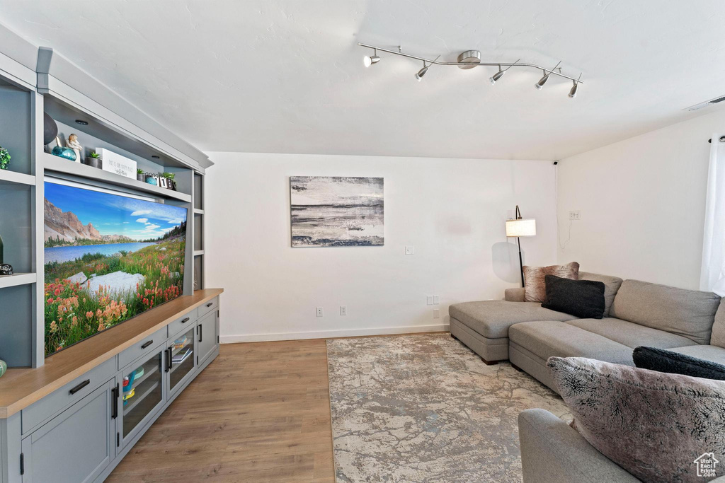 Living room with rail lighting and light hardwood / wood-style flooring