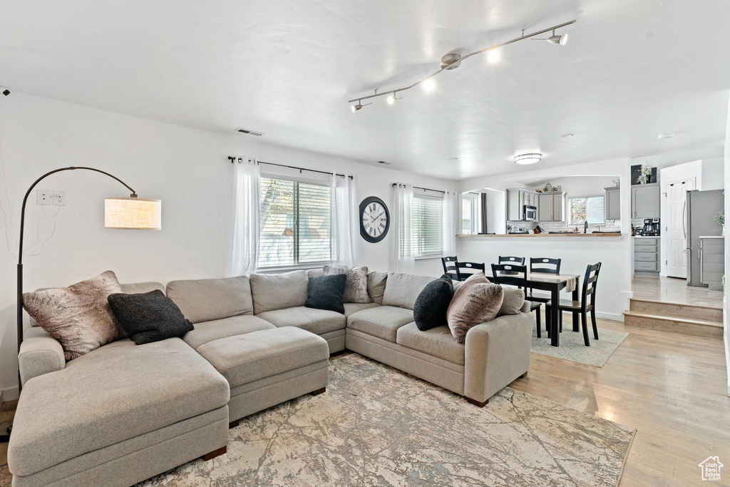 Living room with light hardwood / wood-style floors and rail lighting