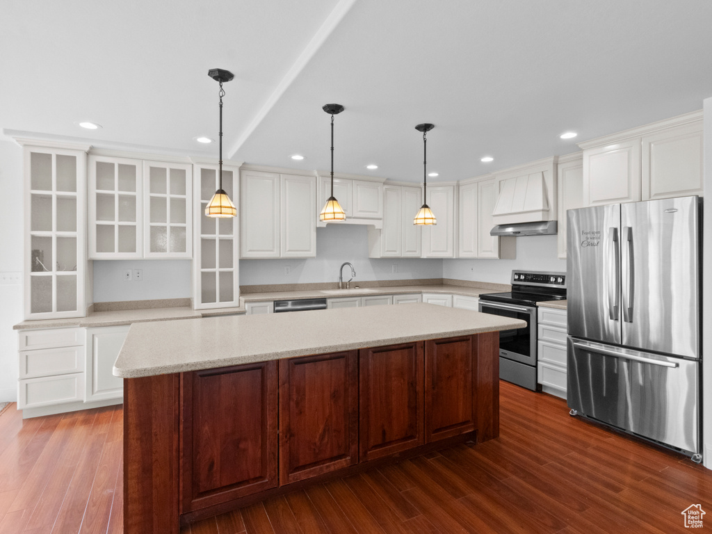 Kitchen featuring a kitchen island, dark hardwood / wood-style floors, stainless steel appliances, and white cabinetry