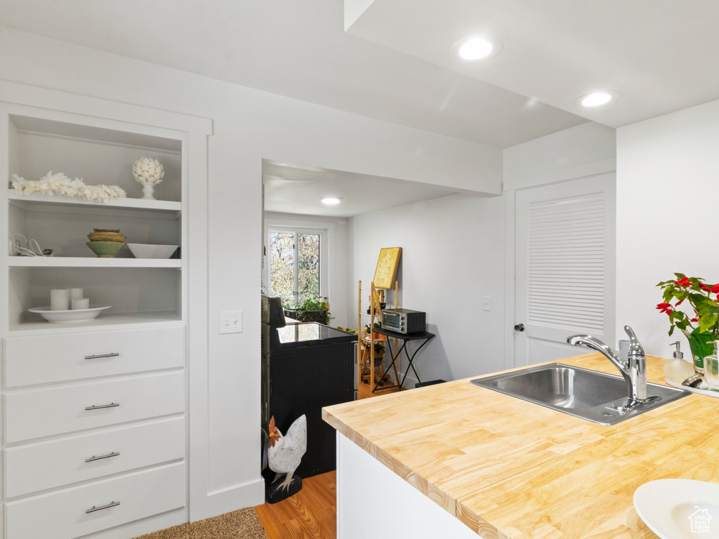 Kitchen featuring butcher block counters, white cabinets, sink, and light wood-type flooring