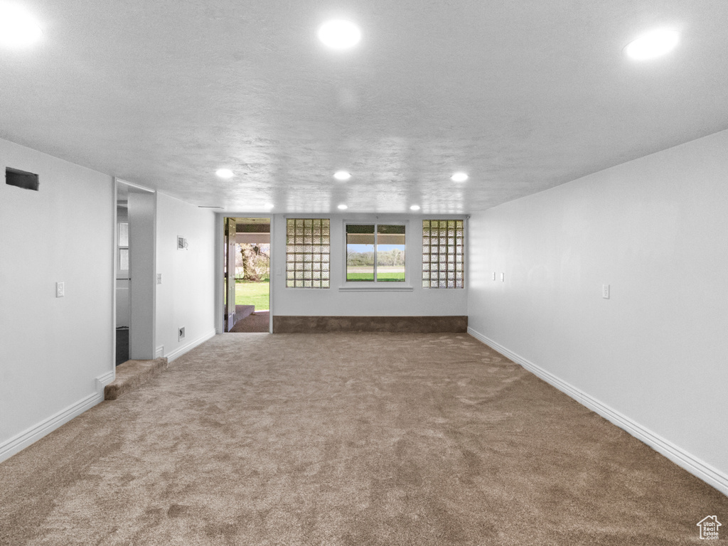 Unfurnished living room with dark carpet and a textured ceiling