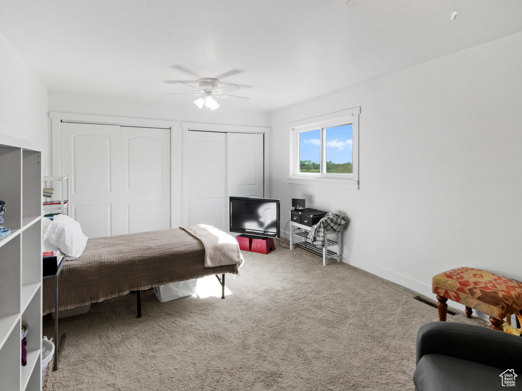 Carpeted bedroom with multiple closets and ceiling fan