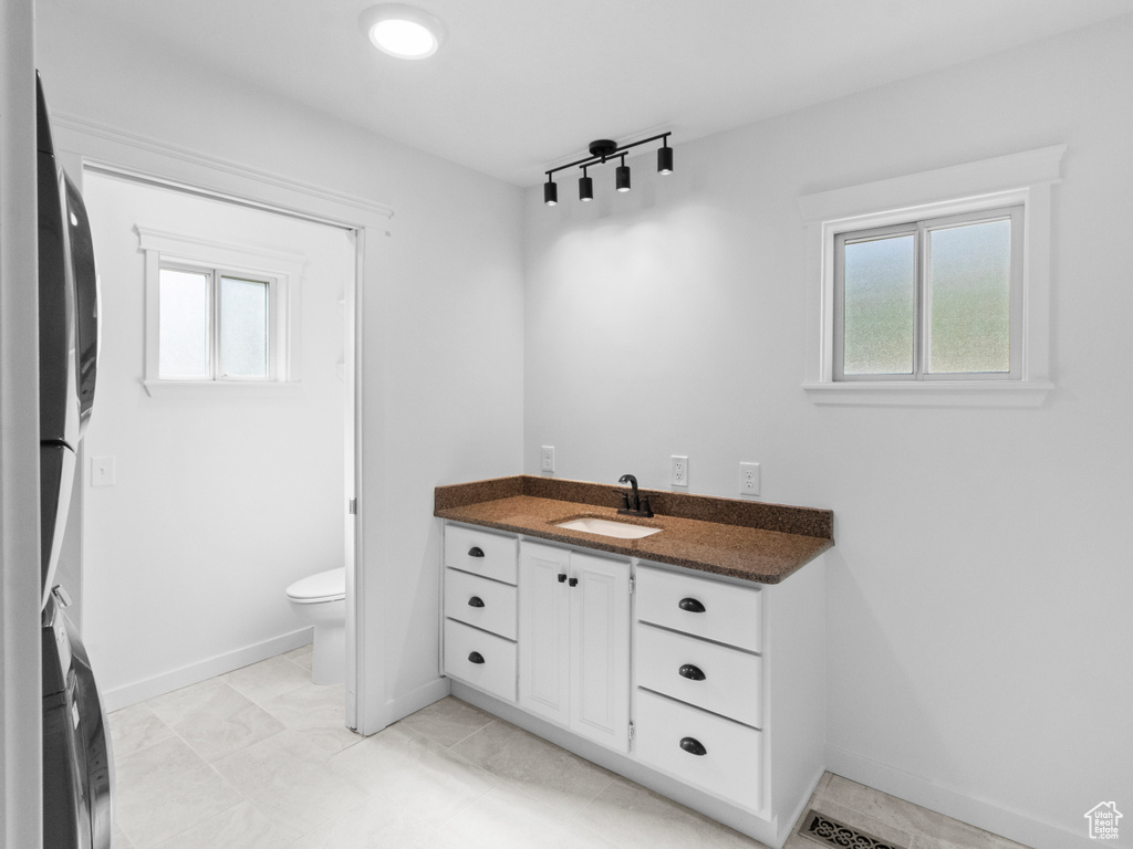 Bathroom with rail lighting, toilet, tile flooring, and vanity