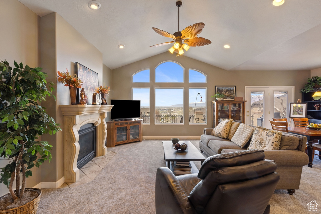 Living room with light colored carpet, plenty of natural light, ceiling fan, and high vaulted ceiling