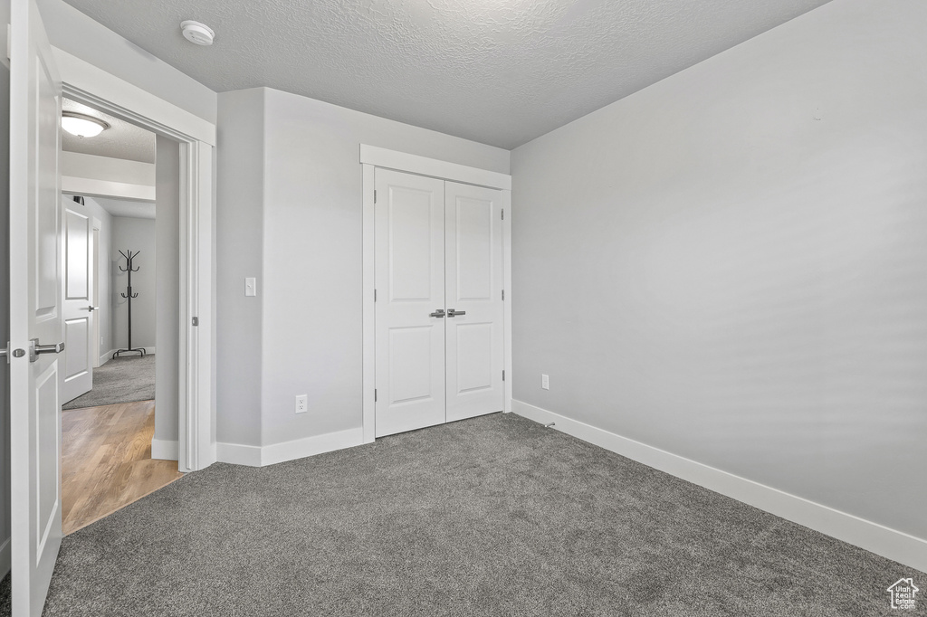 Unfurnished bedroom featuring a closet, hardwood / wood-style flooring, and a textured ceiling