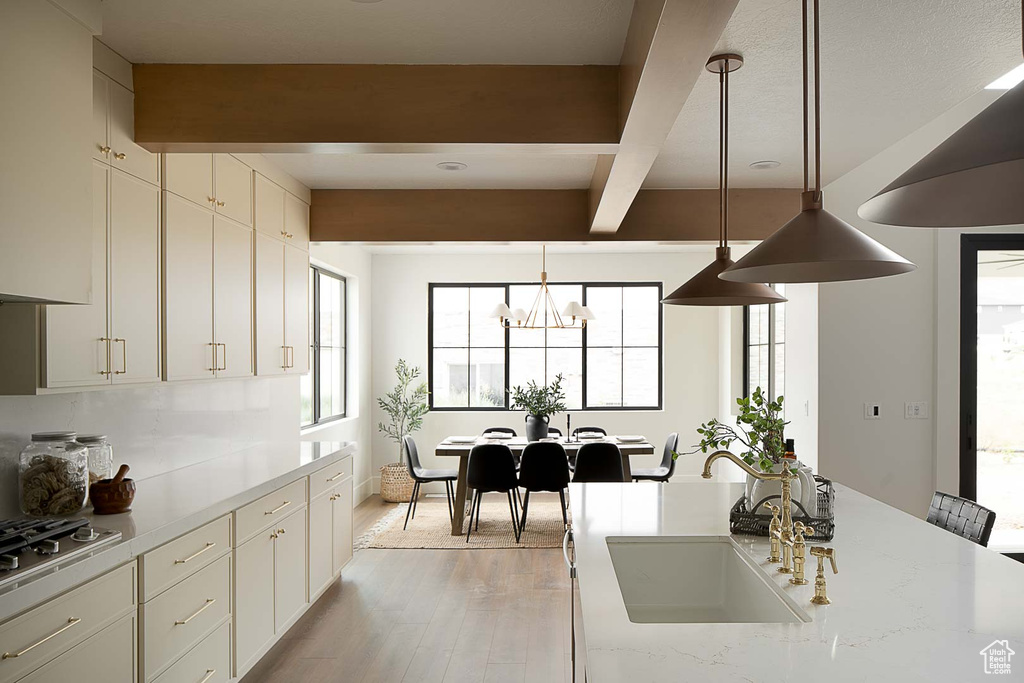 Kitchen featuring beam ceiling, light hardwood / wood-style flooring, sink, and a healthy amount of sunlight