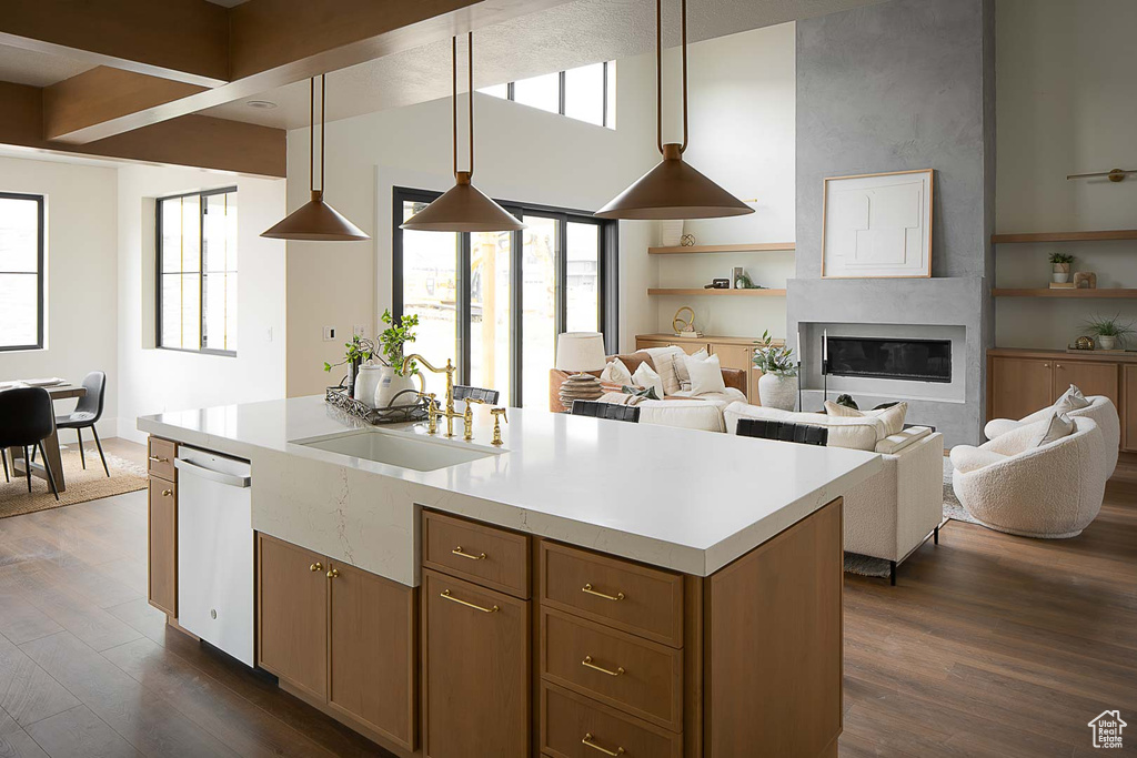 Kitchen with dark wood-type flooring, hanging light fixtures, white dishwasher, sink, and a fireplace