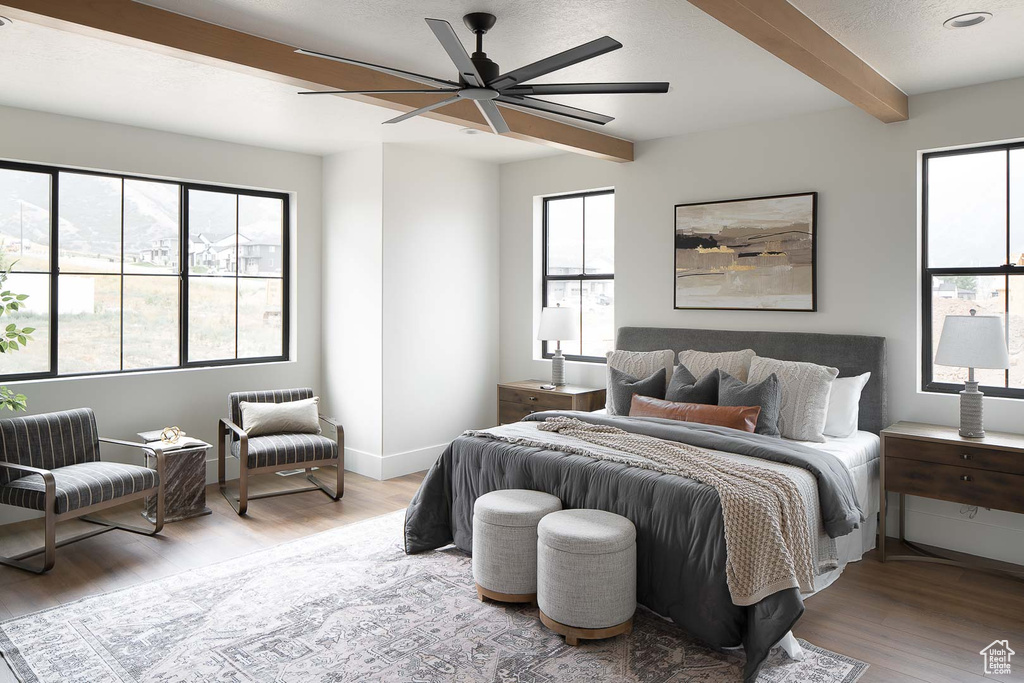 Bedroom featuring beamed ceiling, light wood-type flooring, ceiling fan, and multiple windows