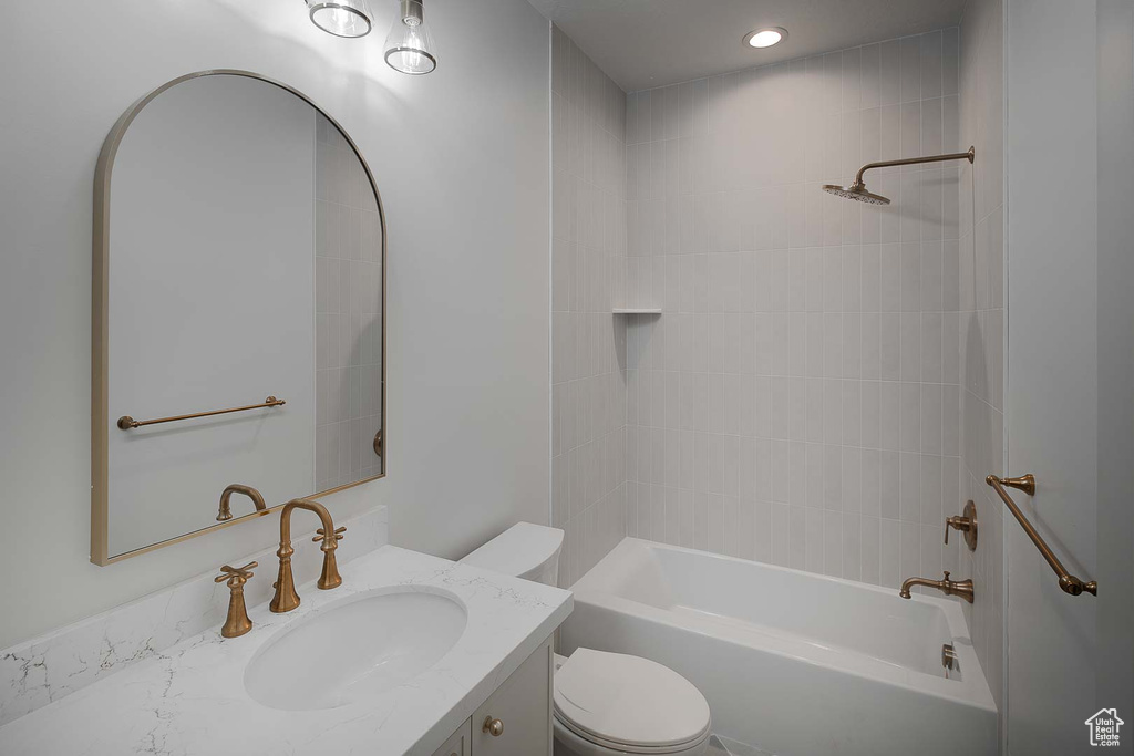 Full bathroom featuring tiled shower / bath combo, vanity, and toilet