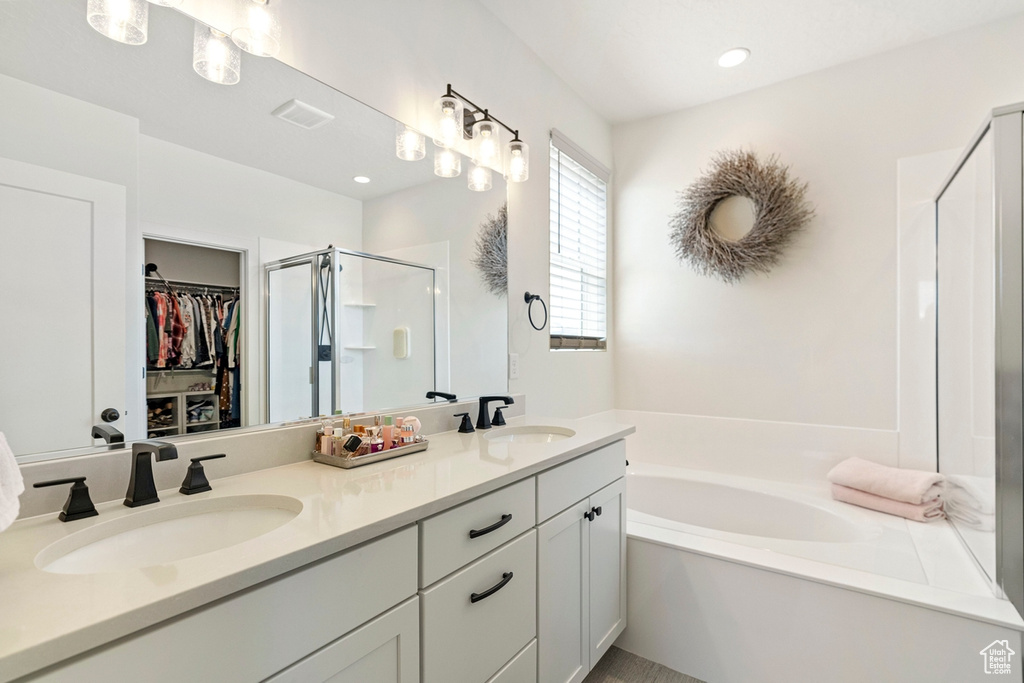 Bathroom with vanity with extensive cabinet space, double sink, and independent shower and bath