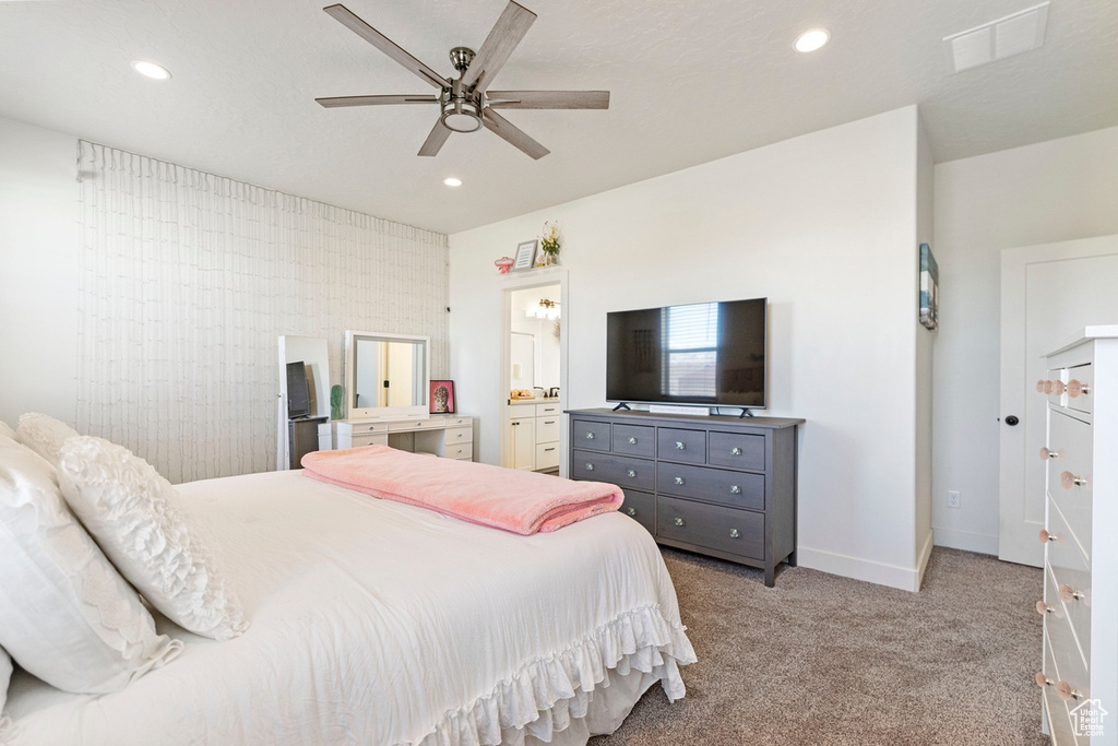 Bedroom with light colored carpet, ceiling fan, and ensuite bathroom