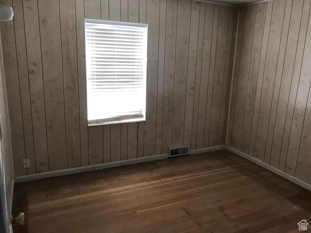 Empty room with wooden walls and dark hardwood / wood-style floors