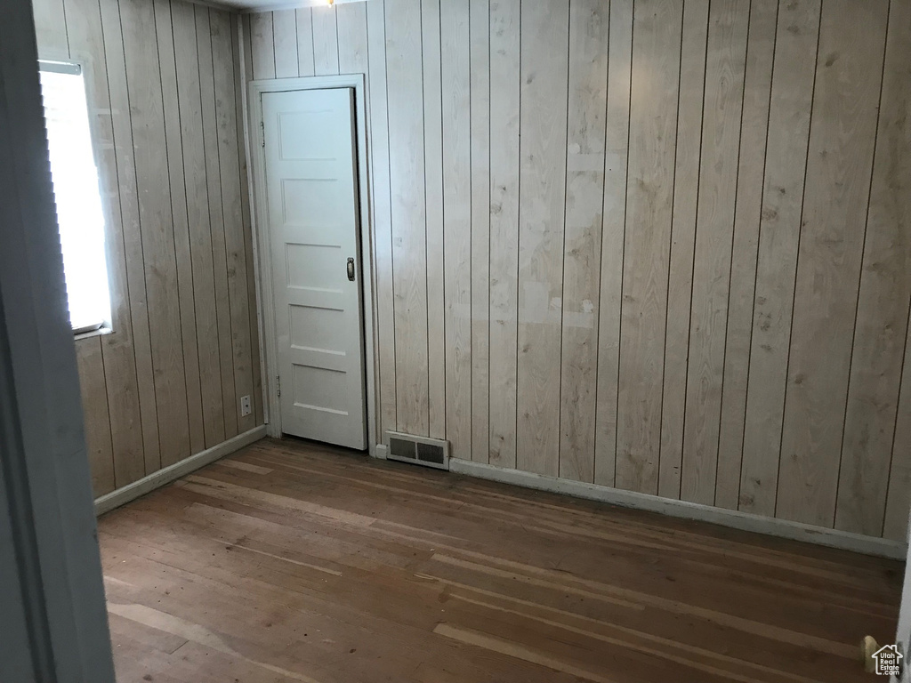 Empty room featuring wooden walls and dark hardwood / wood-style floors
