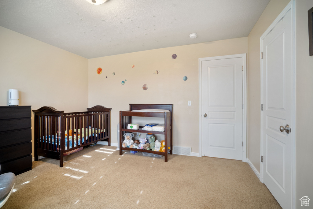 Bedroom with light colored carpet and a nursery area